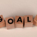 Aligned wooden blocks spelling 'Goals' symbolize target achievement and ambition.