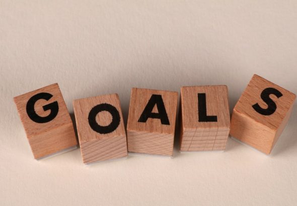 Aligned wooden blocks spelling 'Goals' symbolize target achievement and ambition.